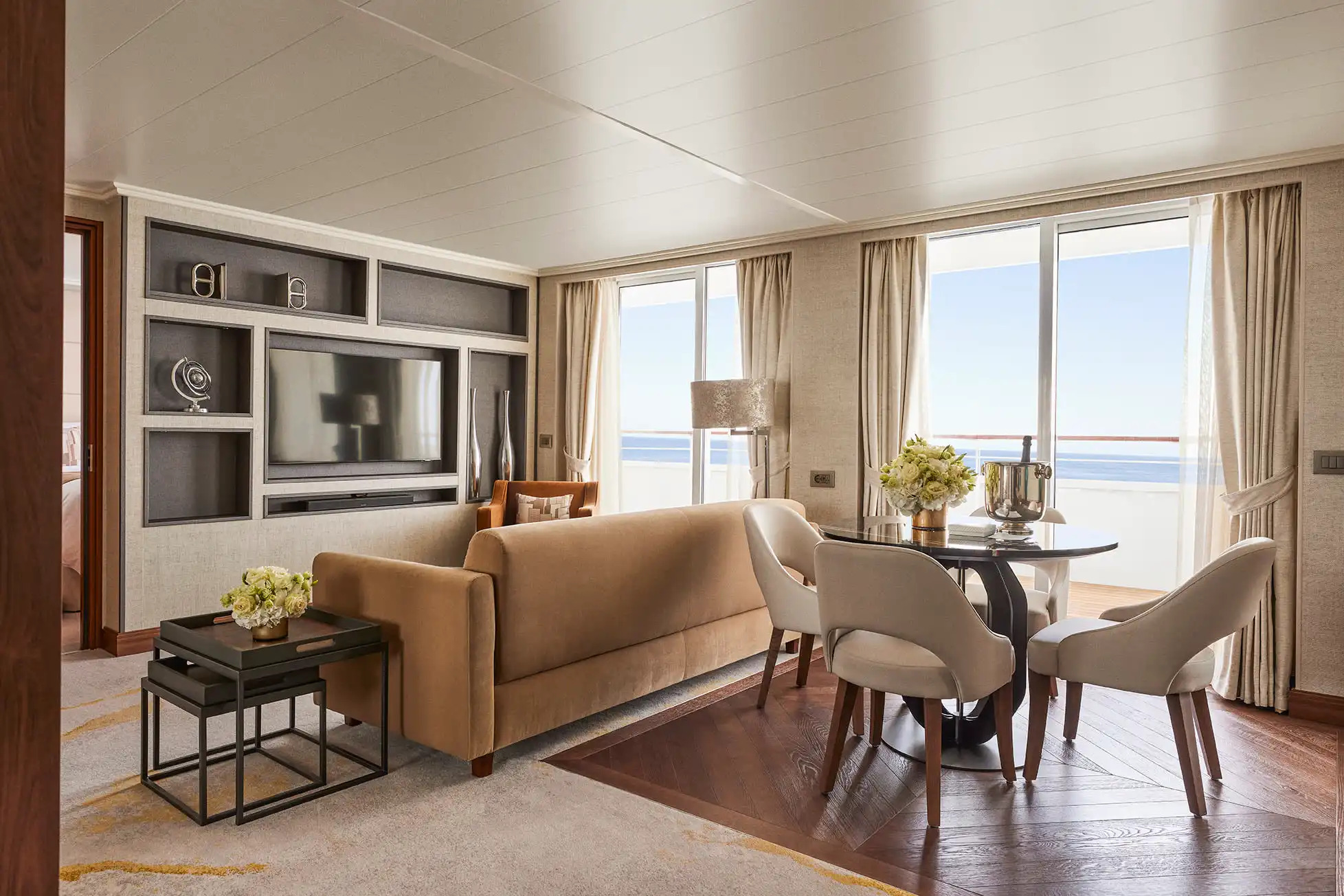 Luxe cruise living room with wooden floors and balcony overlooking the ocean